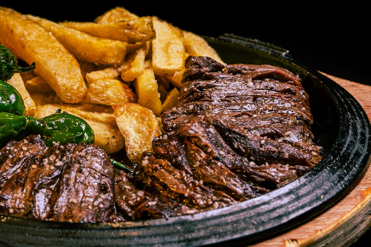 about-03 Juicy grilled steak paired with crispy fries and green peppers on a rustic plate.