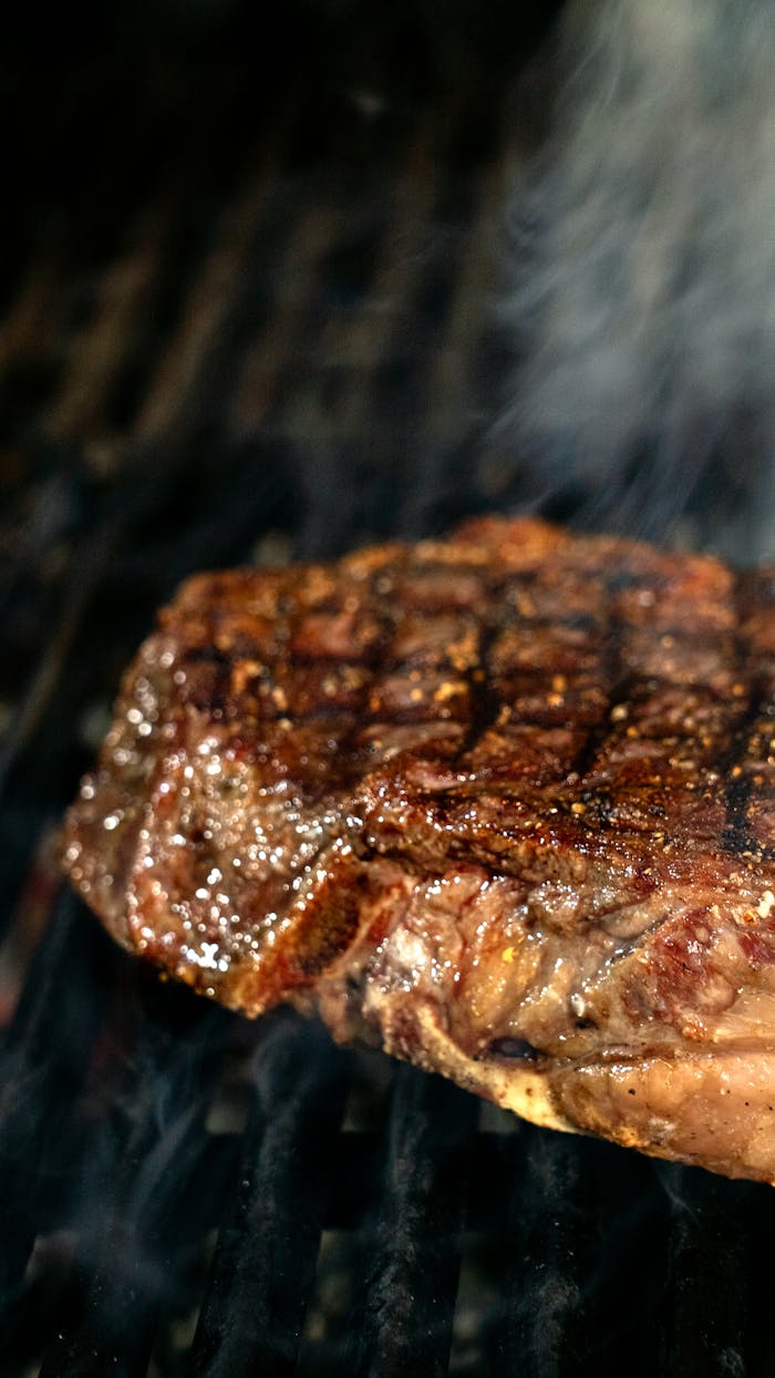 about-02 Close-up of a juicy steak grilling, emitting smoke and showing a perfect sear.